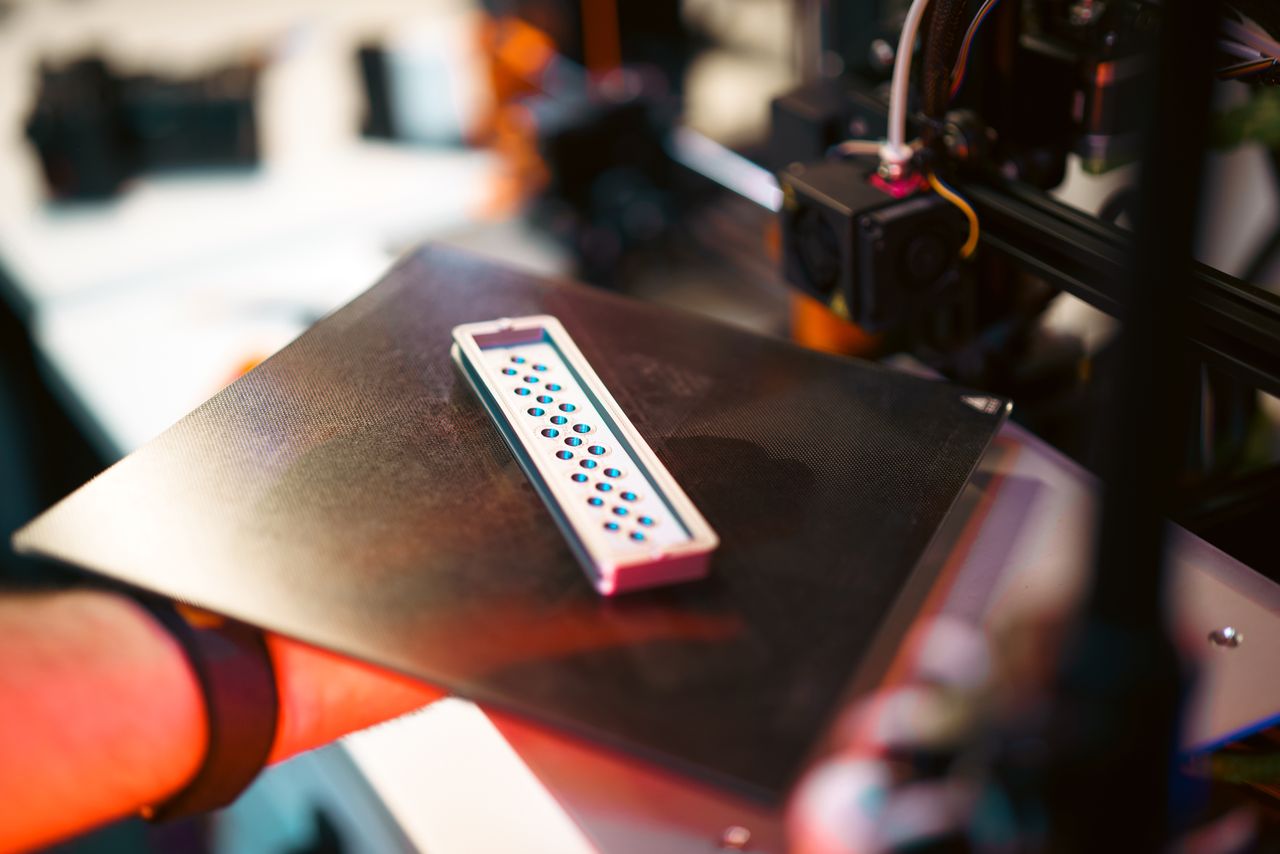 Services Close-up of a 3D printed part on an industrial printer in a workshop setting.
